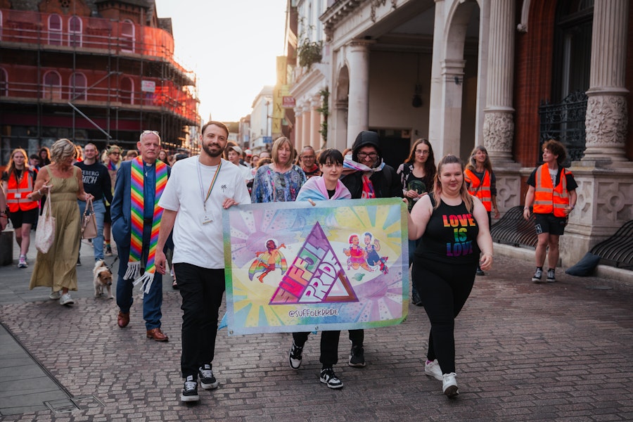 People marching through Ipswich town centre holding a Suffolk pride flag